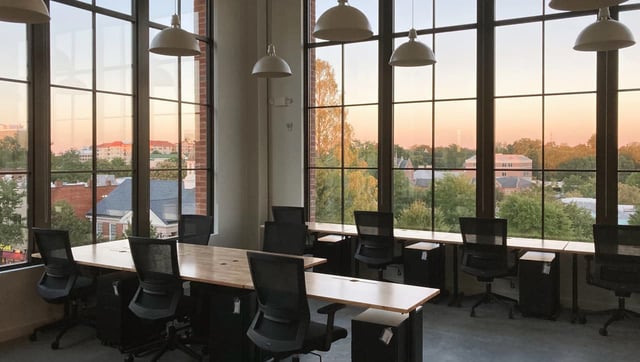 interior-of-a-modern-workspace-with-floor-to-ceiling-windows-pendant-lighting-and-rows-of-chairs-and-tables