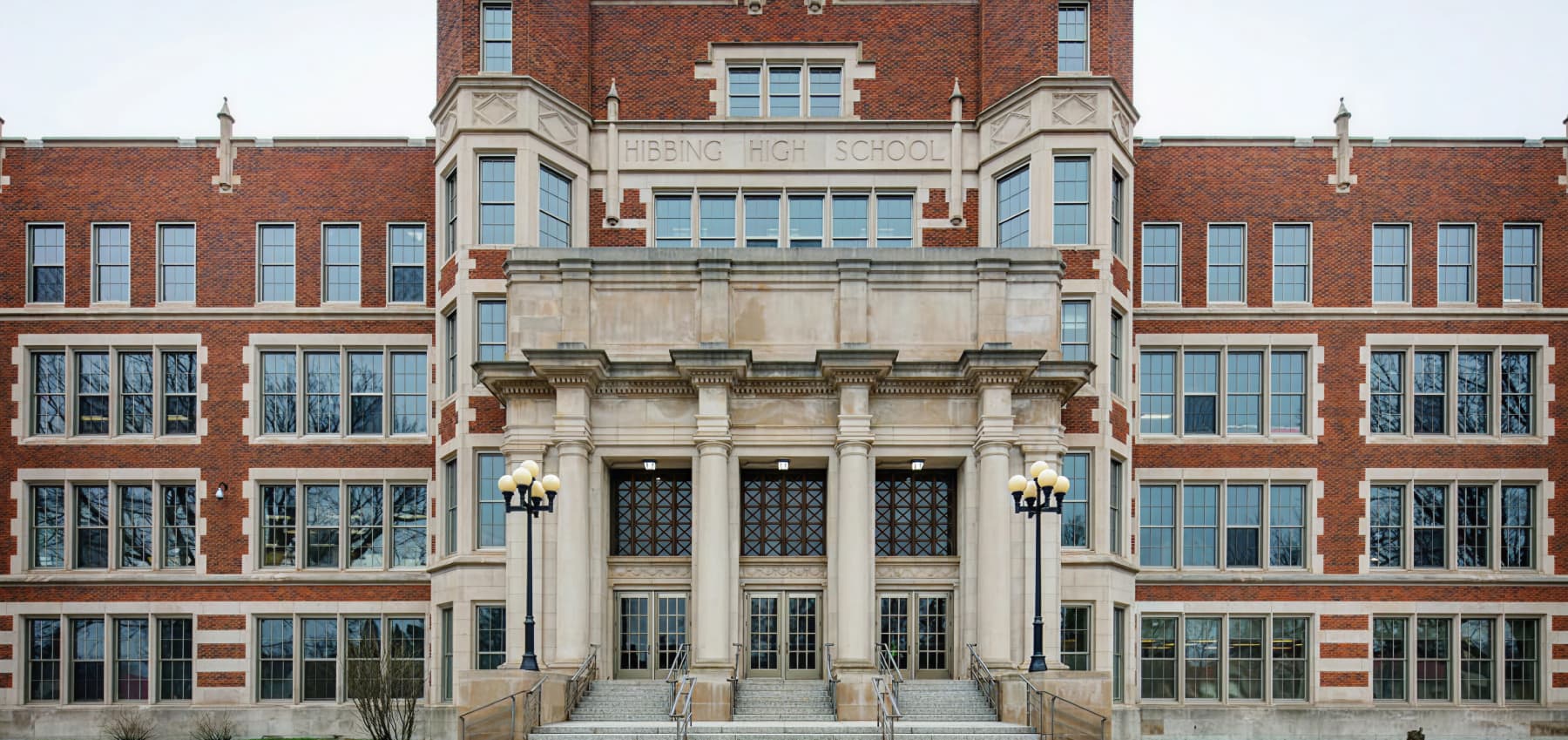 front-facade-of-hibbing-high-school-in-hibbing-minnesota-featuring-historic-brick-architecture-large-multi-pane-windows-and-ornate-stone-entry-columns