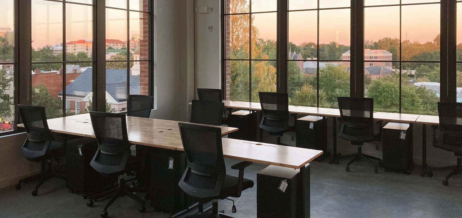 interior-of-a-modern-workspace-with-floor-to-ceiling-windows-pendant-lighting-and-rows-of-chairs-and-tables